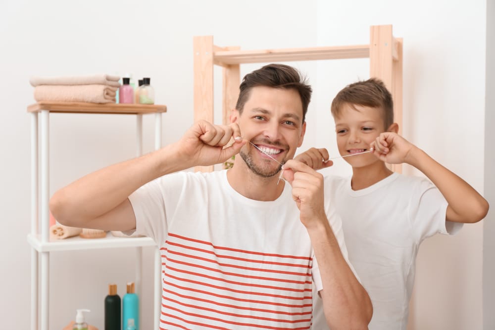father and son flossing teeth