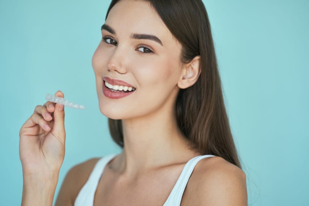beautiful woman holding clear aligners