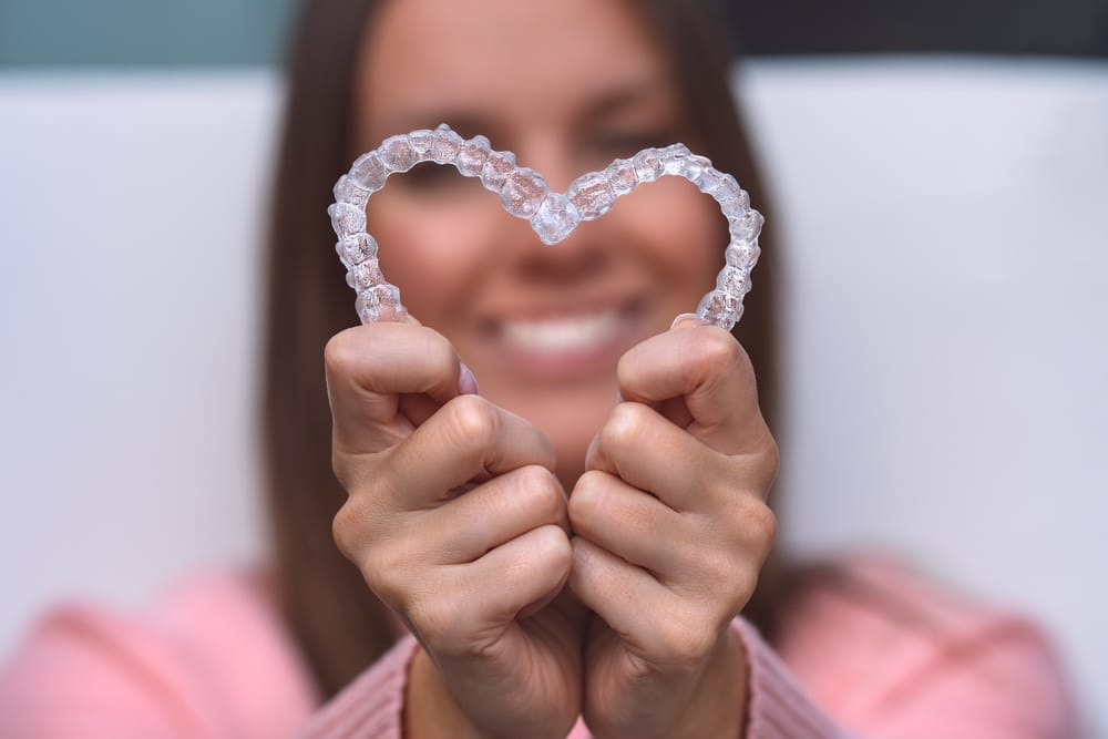 woman holding clear aligners into a heart shape