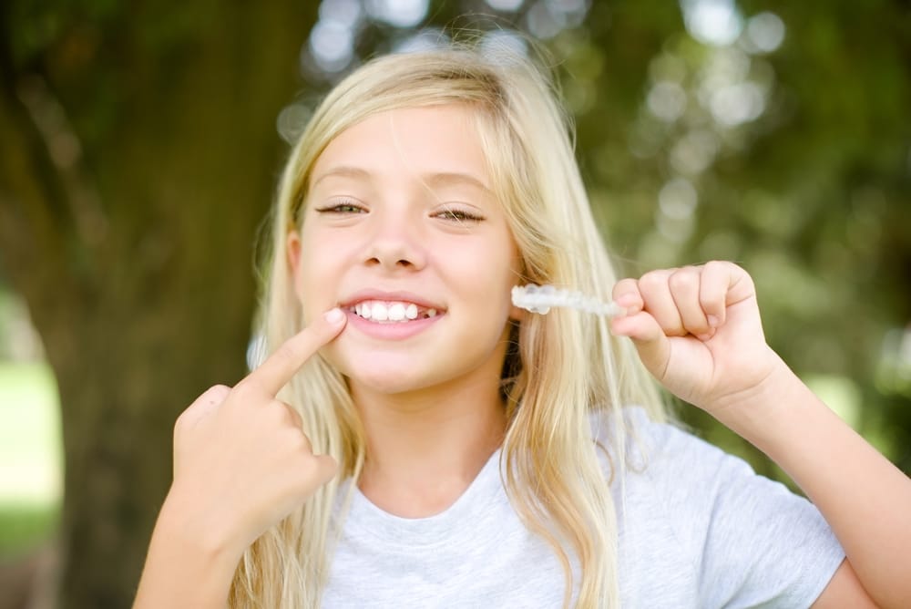 little girl holding clear aligners