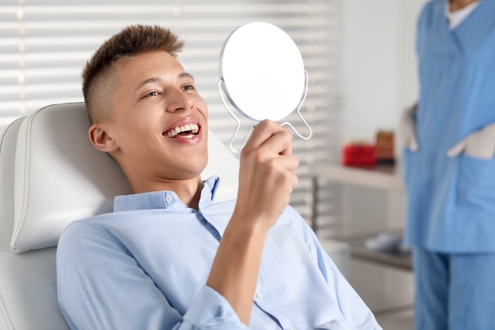 man checking his teeth on a mirror