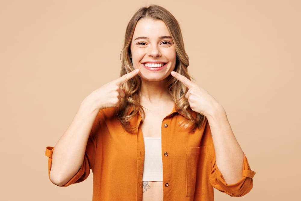 woman wearing orange shirt pointing at teeth