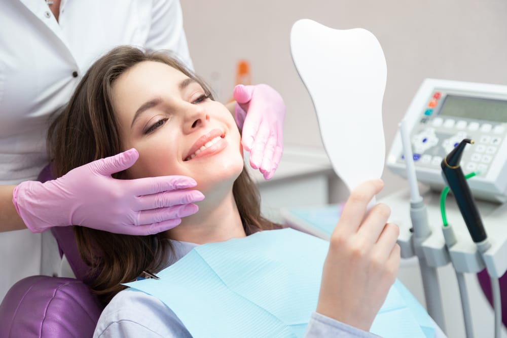 woman checking her teeth at the dentist - Smile Haven logo
