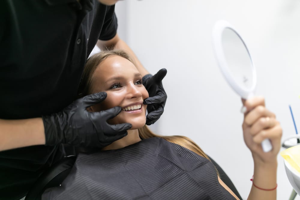 woman at the dentist checking her teeth in a mirror - Dental Implants Orlando